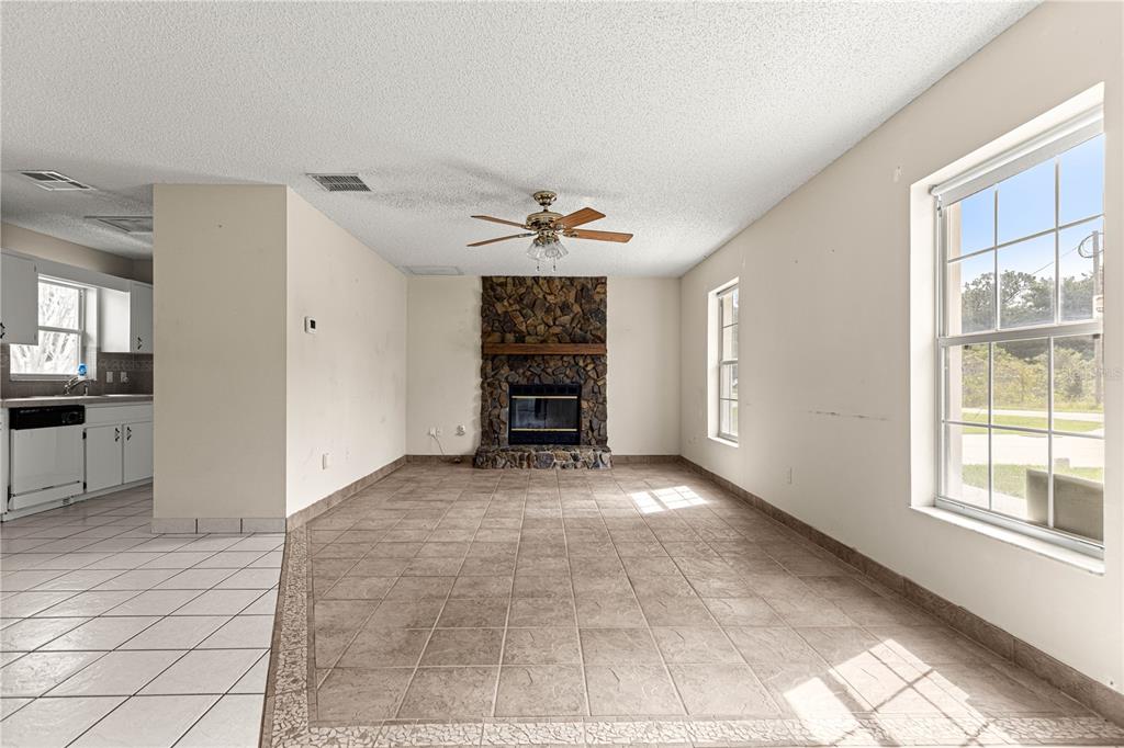 A living room with tile flooring, a stone fireplace, and a ceiling fan — 3805 SE 139TH STREET, SUMMERFIELD, FL