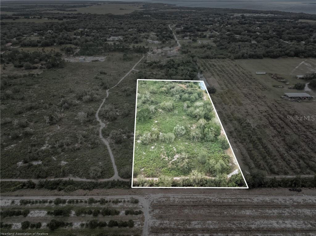 An aerial view shows a rectangular, undeveloped plot of land outlined in white — 701 JOLLY LANE, LORIDA, FL