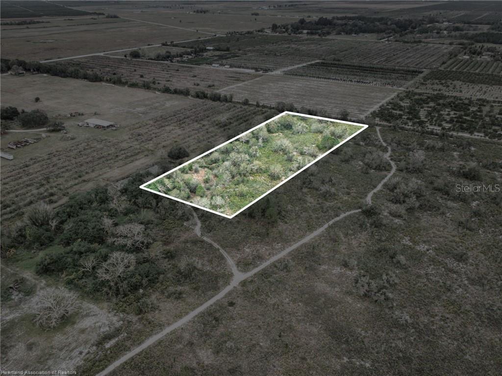 An aerial view shows a rectangular plot of land outlined in white amidst rural fields — 701 JOLLY LANE, LORIDA, FL