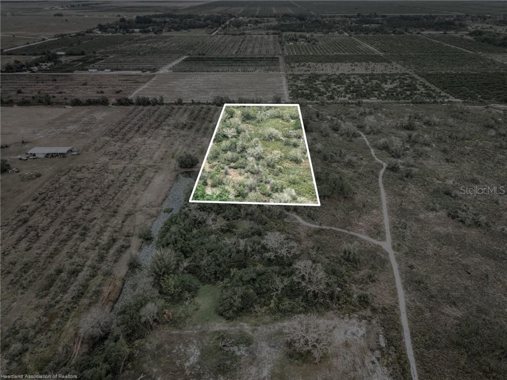 An aerial view shows a rectangular plot of land outlined in white amidst rural vegetation — 701 JOLLY LANE, LORIDA, FL