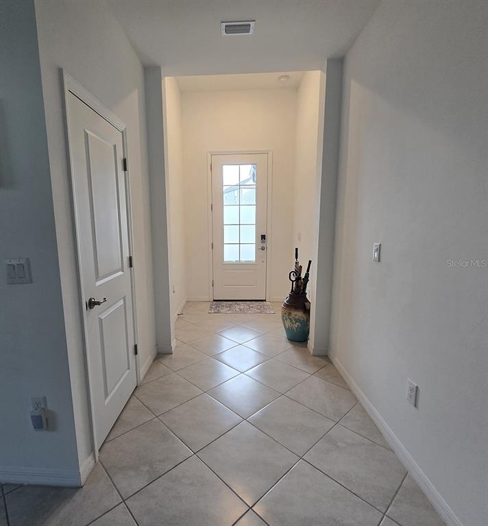 A tiled entryway features a white front door with glass panels and a decorative umbrella stand — 19763 TORTUGA CAY DRIVE, VENICE, FL