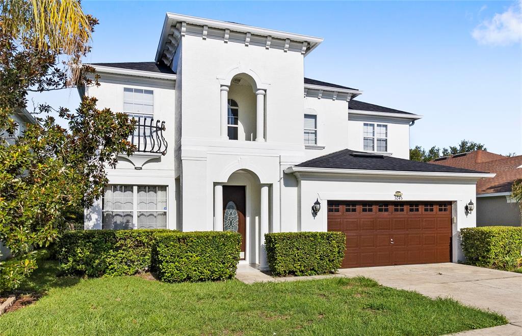 A two-story white stucco house with a brown garage door and a front lawn — 5045 BALLARK STREET, MOUNT DORA, FL