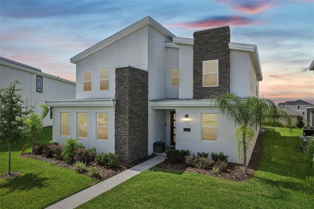 A two-story house with white stucco walls, stone accents, and a front walkway — 9266 SOMMERSET HILLS DRIVE, DAVENPORT, FL
