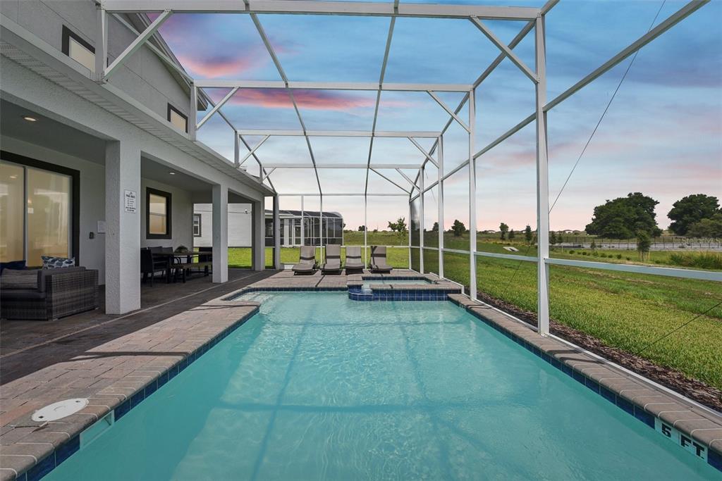 A swimming pool and hot tub are enclosed by a screen cage on a patio — 9266 SOMMERSET HILLS DRIVE, DAVENPORT, FL