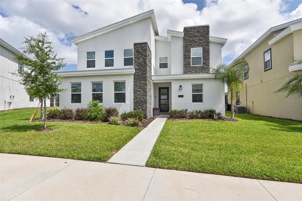 A two-story house with white stucco siding, stone accents, and a concrete walkway — 9266 SOMMERSET HILLS DRIVE, DAVENPORT, FL