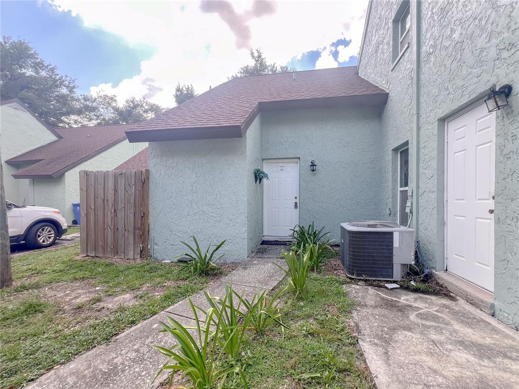 The exterior of a light green stucco townhouse features a white front door and walkway — 12414 N 58TH STREET UNIT 63, TAMPA, FL
