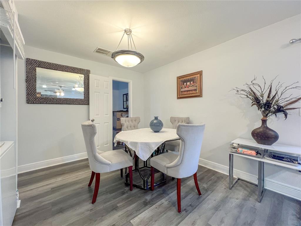 A dining room features a round table with four chairs, a mirror, and wood-look flooring — 12414 N 58TH STREET UNIT 63, TAMPA, FL