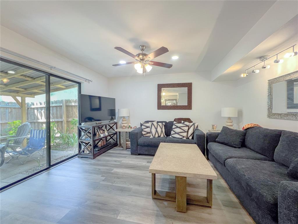 A living room features dark gray sofas, a coffee table, and a sliding glass door — 12414 N 58TH STREET UNIT 63, TAMPA, FL
