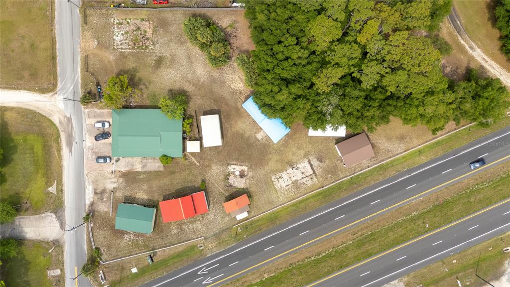 An aerial view shows a property with multiple buildings, outbuildings, and trees near a highway — 3526 ELLIS LANE, MIMS, FL