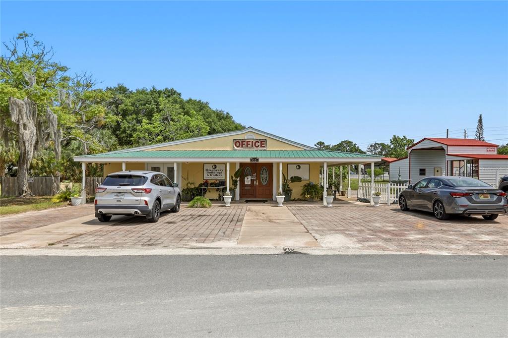 A yellow office building with a green metal roof and two parked cars in front — 3526 ELLIS LANE, MIMS, FL