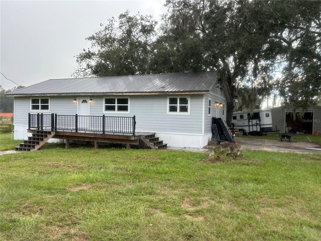 A light gray single-story house with a metal roof and a wooden deck — 10661 W HIGHWAY 40, OCALA, FL