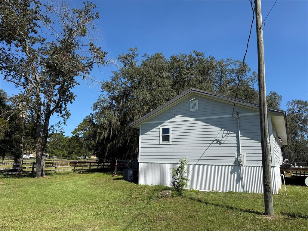 A light gray house with white corrugated metal siding sits on a grassy lot — 10661 W HIGHWAY 40, OCALA, FL