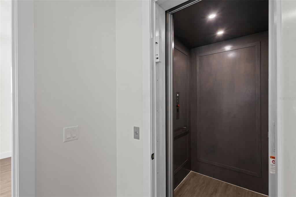 An indoor elevator with dark wood-paneled walls is situated next to a white wall — 7414 MAKO DRIVE, HUDSON, FL