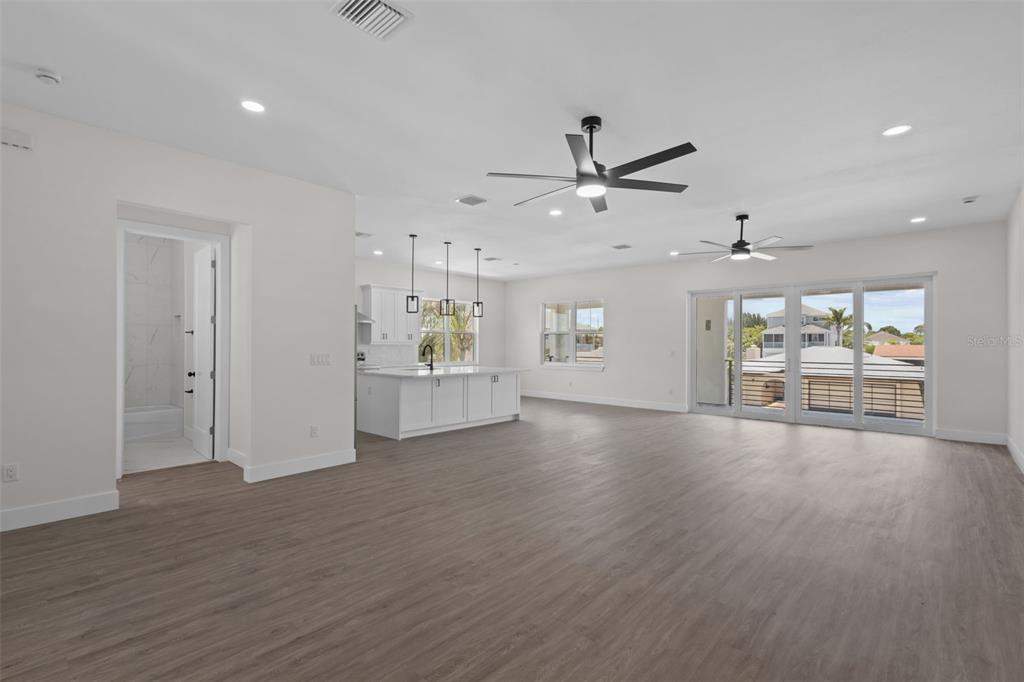 An open-concept living area features a kitchen with a white island and sliding glass doors — 7414 MAKO DRIVE, HUDSON, FL