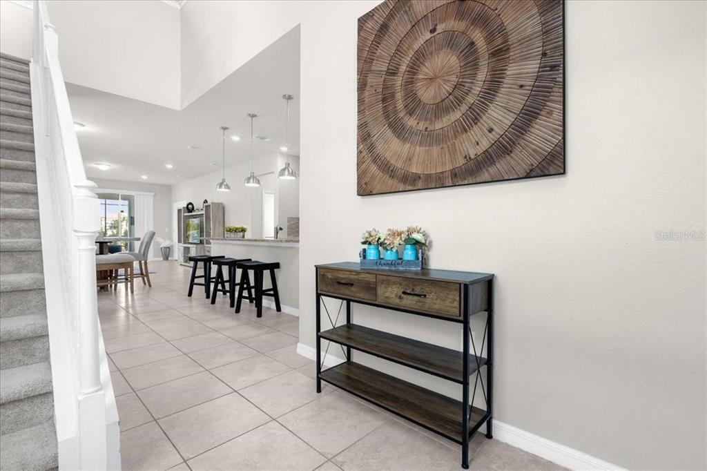 A foyer with a staircase, a console table, and a view into an open-concept kitchen — 7211 OAKMOSS LOOP, DAVENPORT, FL
