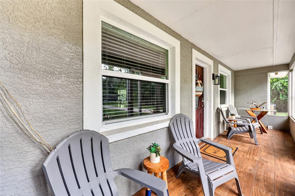 A covered porch features grey chairs, a small wooden table, and wood-look tile flooring — 1920 NW 15TH AVENUE, CRYSTAL RIVER, FL