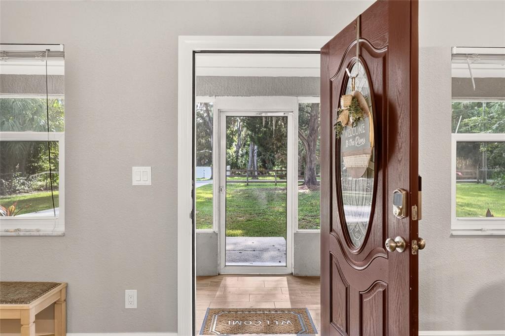An open front door reveals a screened-in porch with a view of a grassy yard — 1920 NW 15TH AVENUE, CRYSTAL RIVER, FL