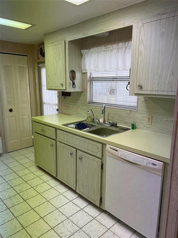 A kitchen features light green wood-grain cabinets, laminate countertops, a double sink, and white appliances — 201 ROYAL PALM CIRCLE, LARGO, FL