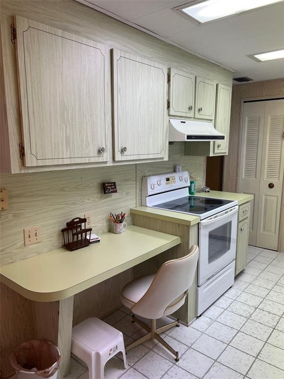 A kitchen features light wood-grain cabinets, a built-in desk area, and a white electric range — 201 ROYAL PALM CIRCLE, LARGO, FL