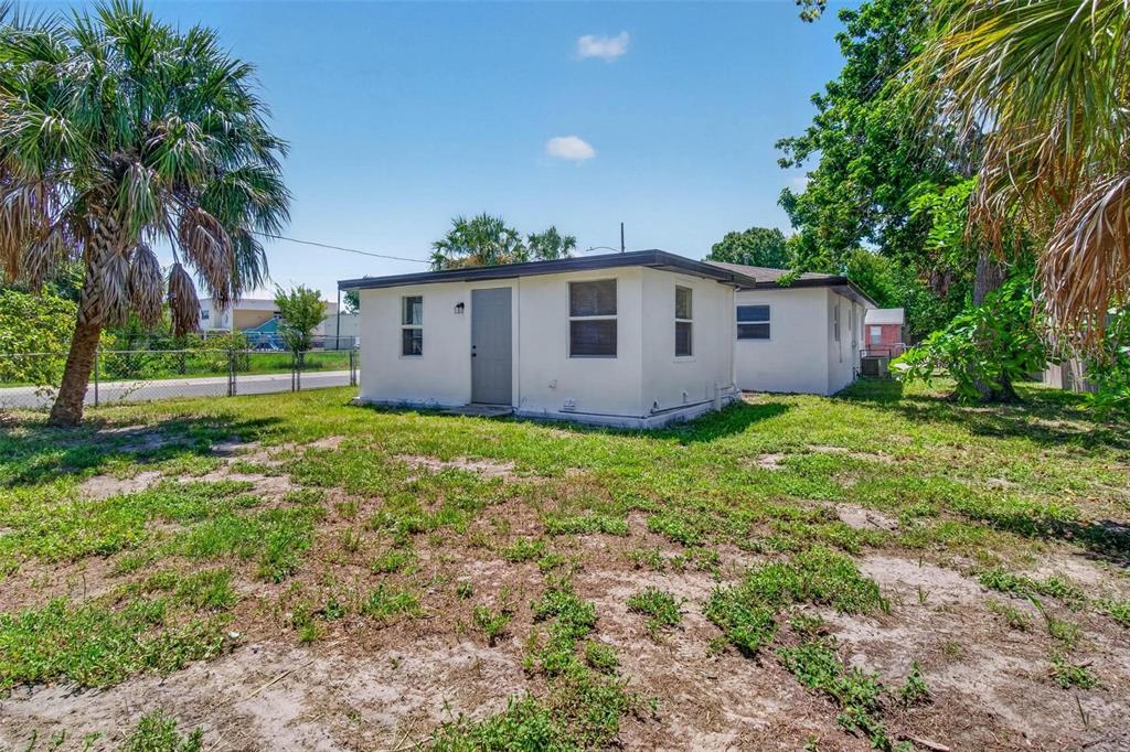 A single-story white house with a flat roof sits on a grassy lot with trees — 1901 MELROSE AVENUE S, ST PETERSBURG, FL