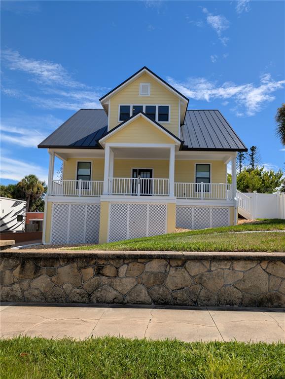 A yellow two-story house with a metal roof and a raised front porch — 414 JESSAMINE BOULEVARD, DAYTONA BEACH, FL