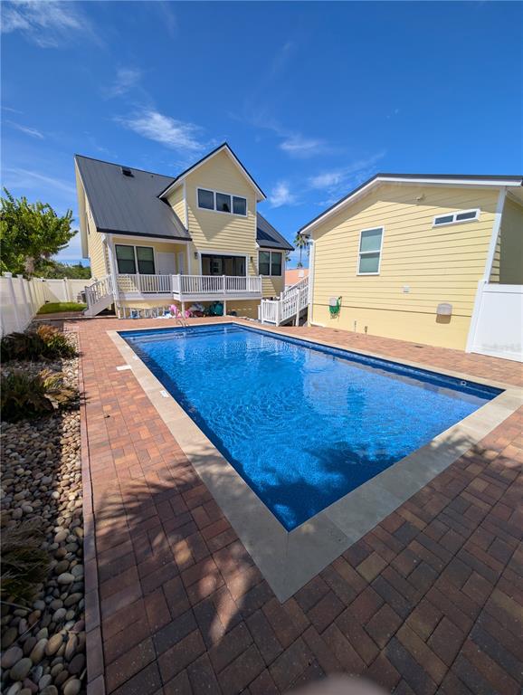 A yellow two-story house with a metal roof overlooks a rectangular backyard swimming pool — 414 JESSAMINE BOULEVARD, DAYTONA BEACH, FL