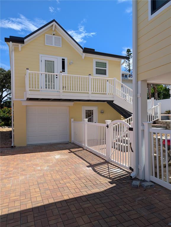A yellow two-story house features a garage, an exterior staircase, and a white picket fence — 414 JESSAMINE BOULEVARD, DAYTONA BEACH, FL