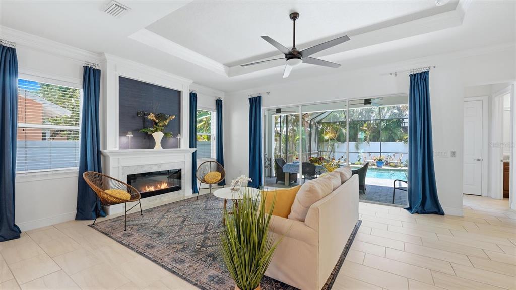 A living room with a fireplace, blue curtains, and a view of a backyard pool — 1850 MAGNOLIA STREET, SARASOTA, FL