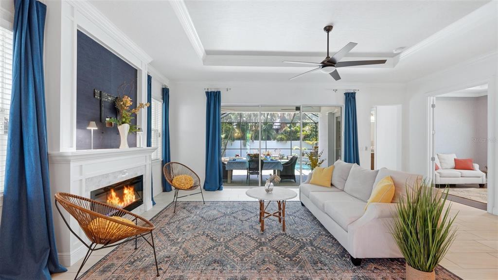 A living room features a fireplace, blue curtains, a patterned rug, and a ceiling fan — 1850 MAGNOLIA STREET, SARASOTA, FL