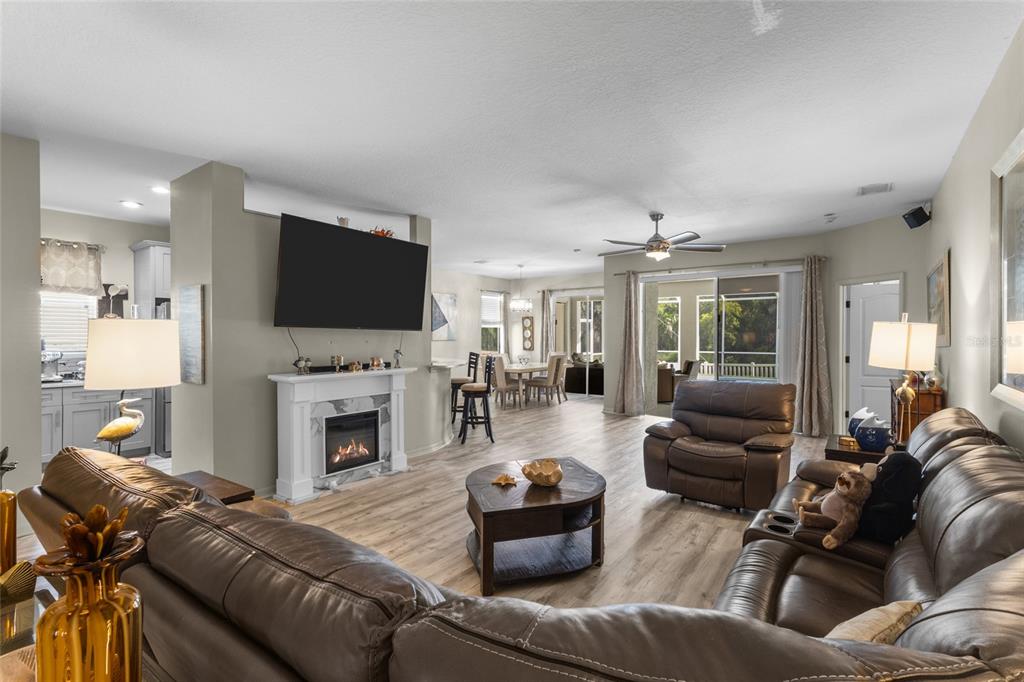 A living room with a fireplace, television, and leather furniture opens to a dining area — 4527 FERRYS MILL PLACE, ELLENTON, FL