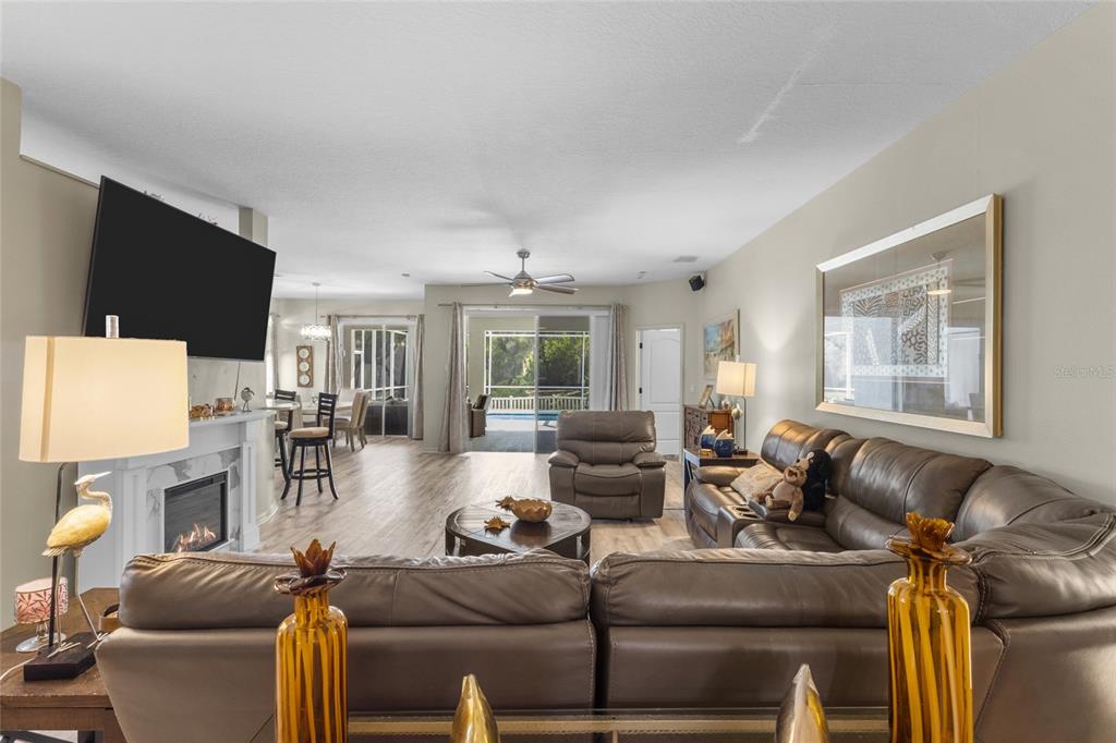 A living room features a leather sectional, a fireplace with a television, and sliding doors — 4527 FERRYS MILL PLACE, ELLENTON, FL