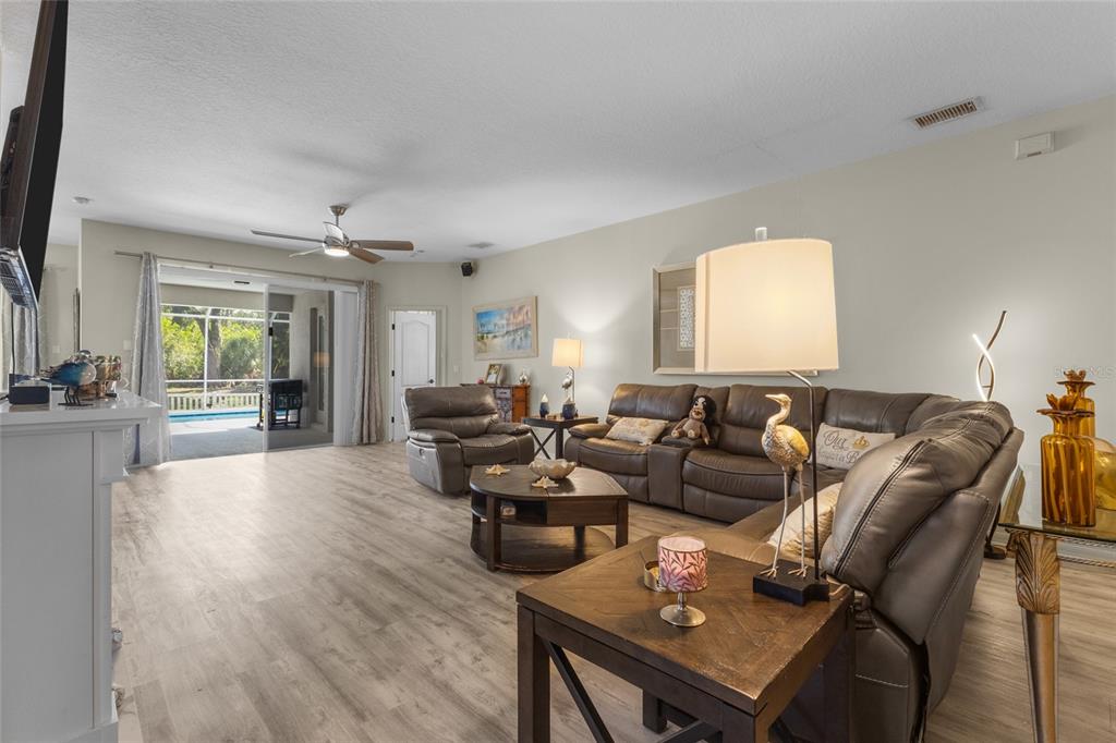 A living room features wood-look flooring, a leather sectional, a recliner, and sliding glass doors — 4527 FERRYS MILL PLACE, ELLENTON, FL