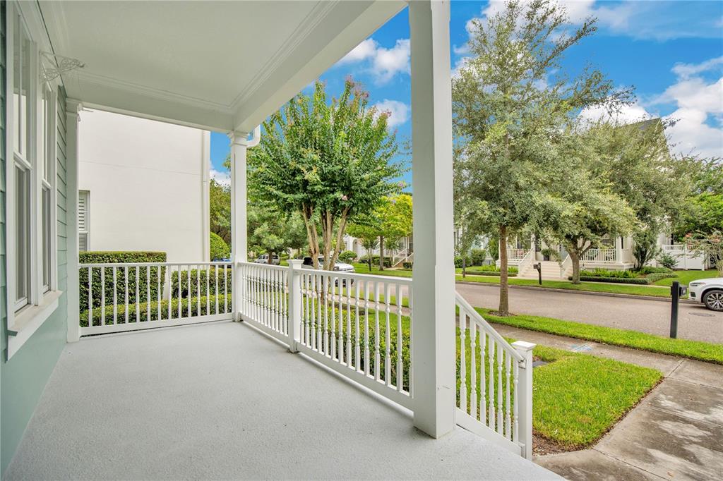 A covered front porch with white railings overlooks a suburban street with trees and houses — 4041 HAWS LANE, ORLANDO, FL