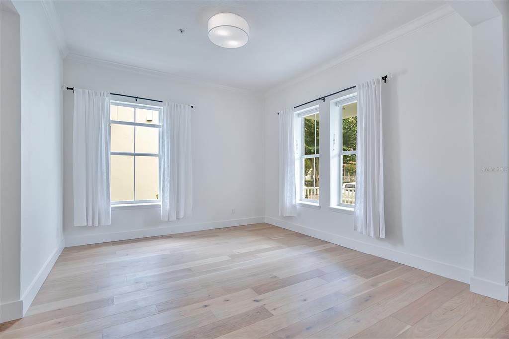 An empty room features white walls, light wood flooring, and three windows with white curtains — 4041 HAWS LANE, ORLANDO, FL