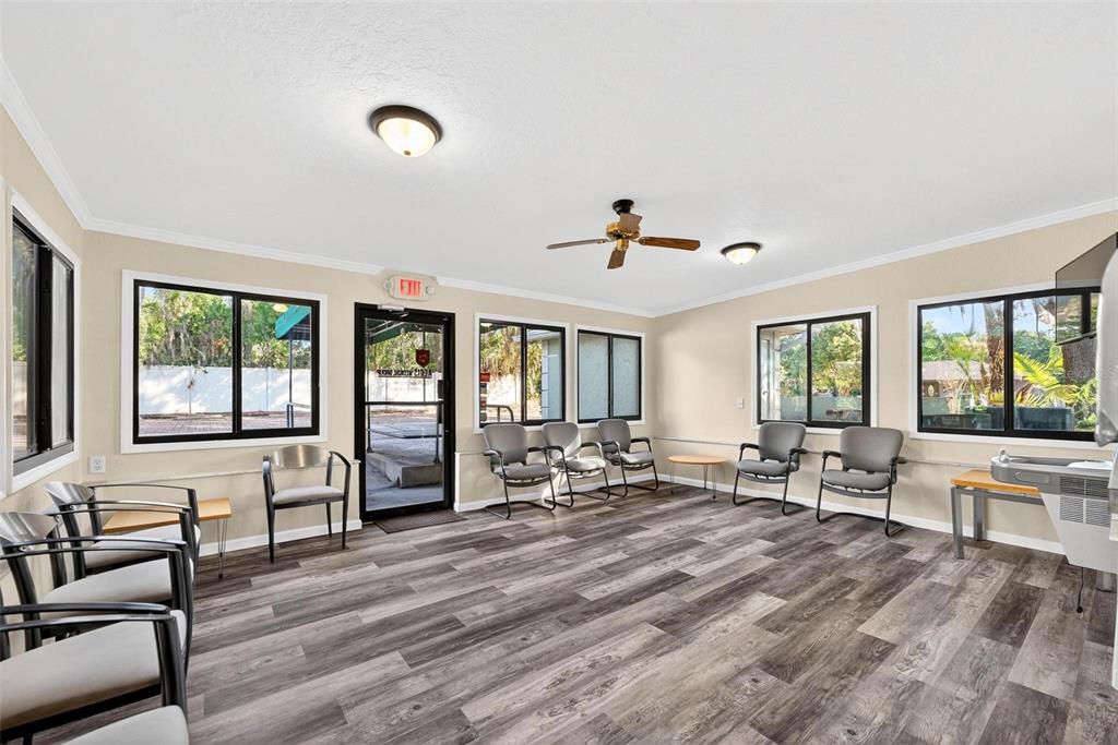 A waiting room features gray wood-look flooring, multiple chairs, large windows, and a ceiling fan — 1318 S EUSTIS STREET, EUSTIS, FL