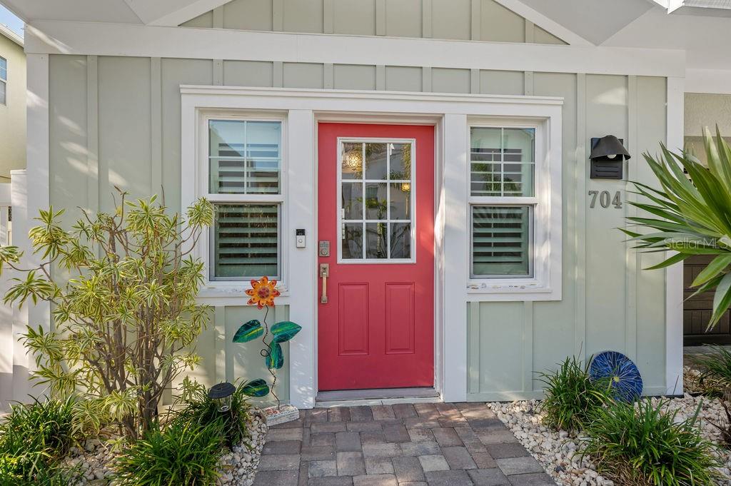 A bright red front door is centered on the light green exterior of a house — 704 GLADIOLUS STREET, ANNA MARIA, FL