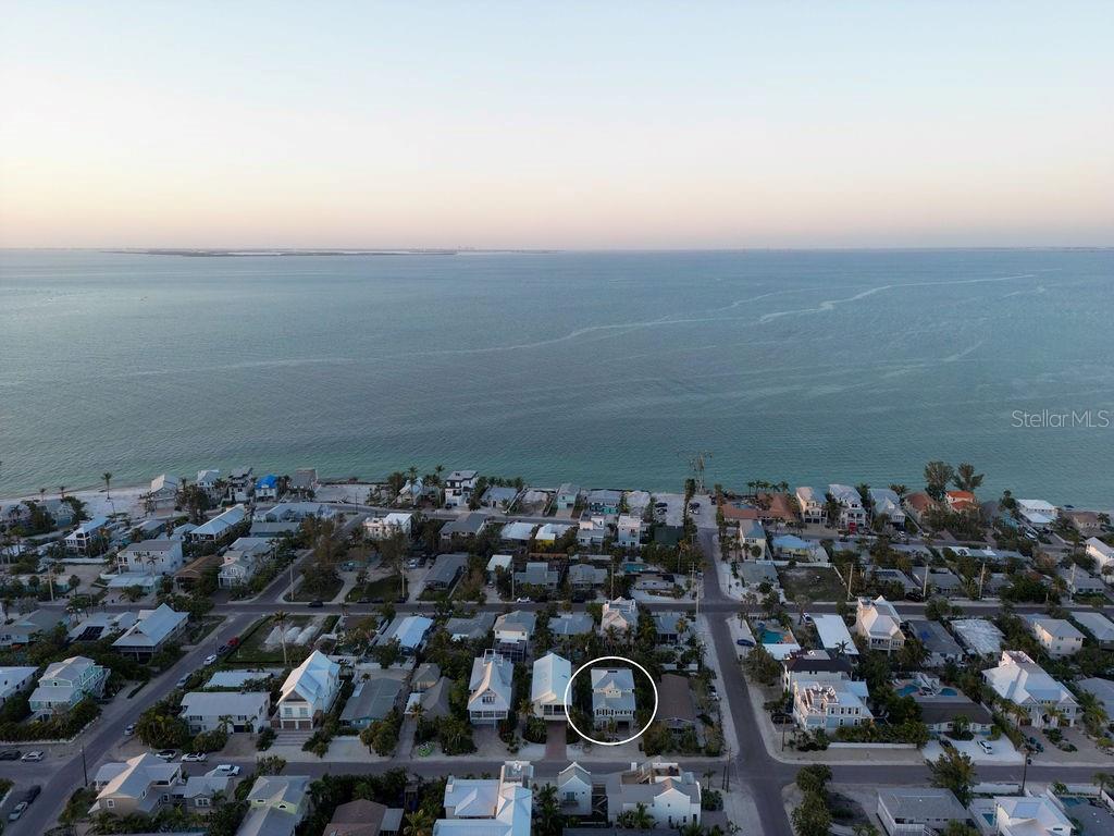 An aerial view shows a coastal neighborhood with a circled house near the water — 704 GLADIOLUS STREET, ANNA MARIA, FL