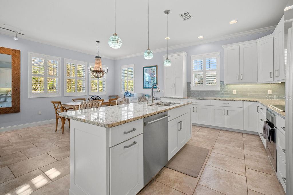 A kitchen with white cabinetry, granite countertops, a central island, and tile flooring — 704 GLADIOLUS STREET, ANNA MARIA, FL
