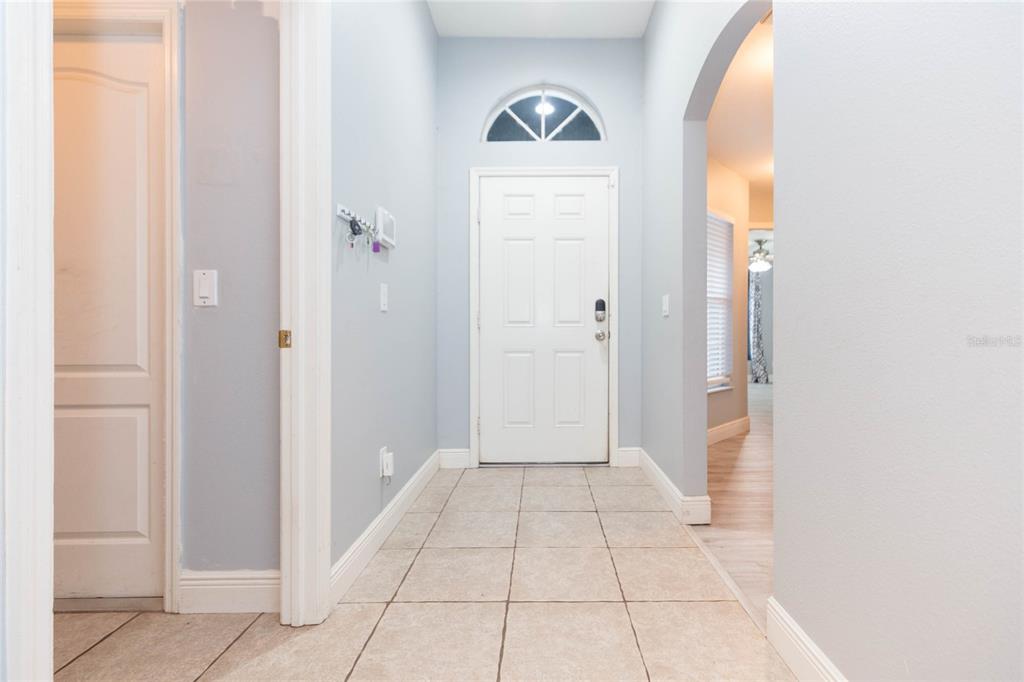 An entryway features light blue walls, beige tile flooring, and a white front door — 11706 PURE PEBBLE DRIVE, RIVERVIEW, FL