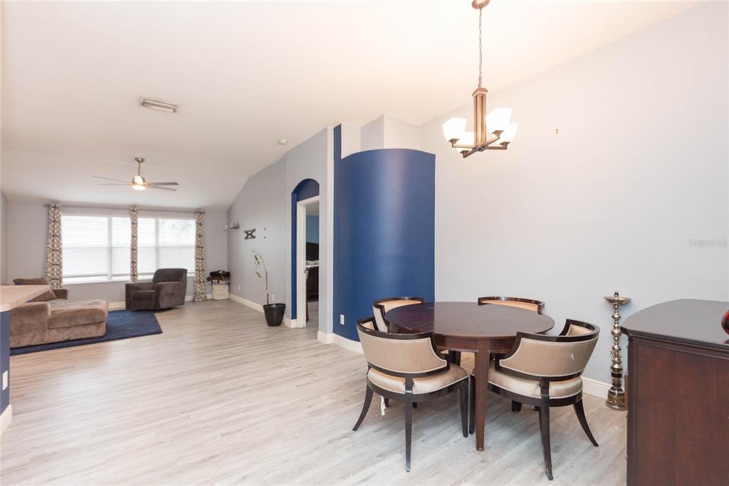 A dining area with a round table and chairs sits adjacent to an open living room — 11706 PURE PEBBLE DRIVE, RIVERVIEW, FL