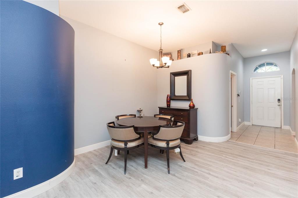 A dining area features a round table, four chairs, a dark dresser, and light flooring — 11706 PURE PEBBLE DRIVE, RIVERVIEW, FL