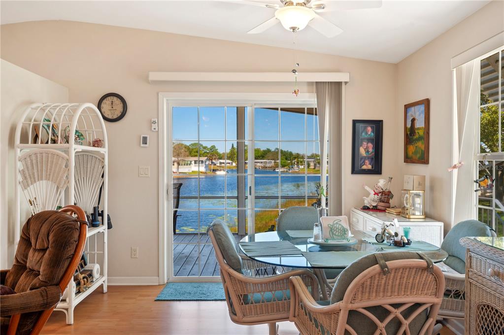 A dining area with a glass table, wicker chairs, and sliding doors overlooking a lake — 38 QUEEN OF WATERS STREET, LAKE WALES, FL