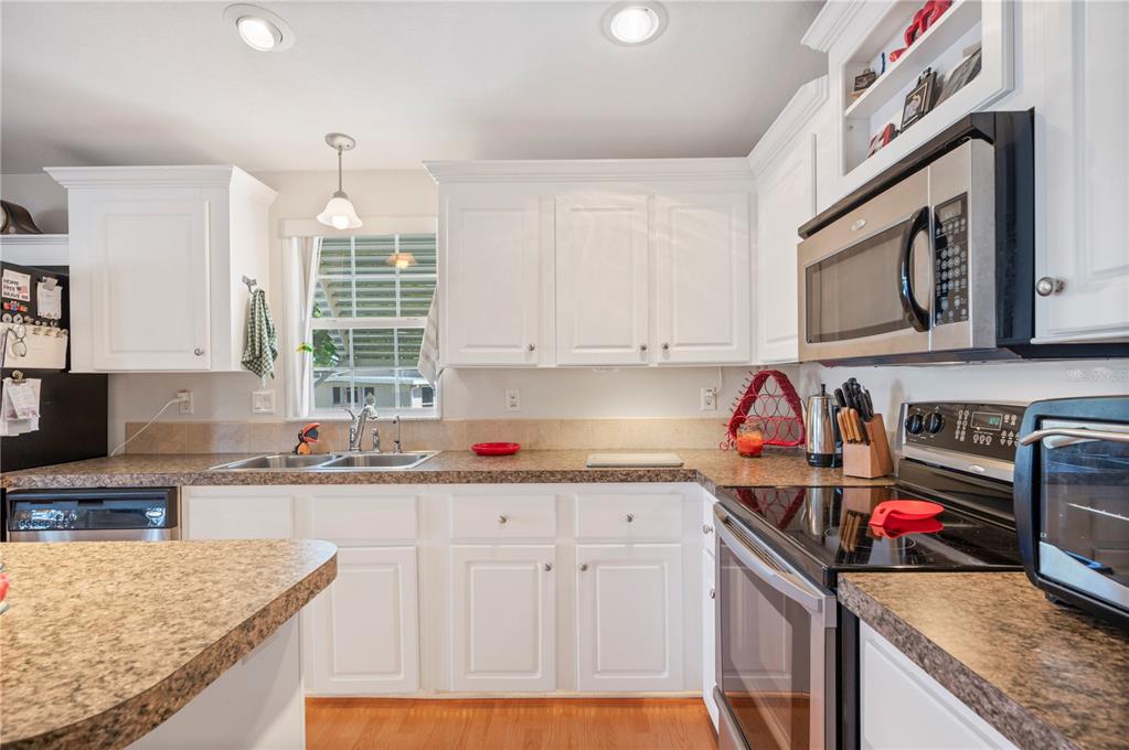 A kitchen with white cabinets, granite countertops, stainless steel appliances, and a window above the sink — 38 QUEEN OF WATERS STREET, LAKE WALES, FL
