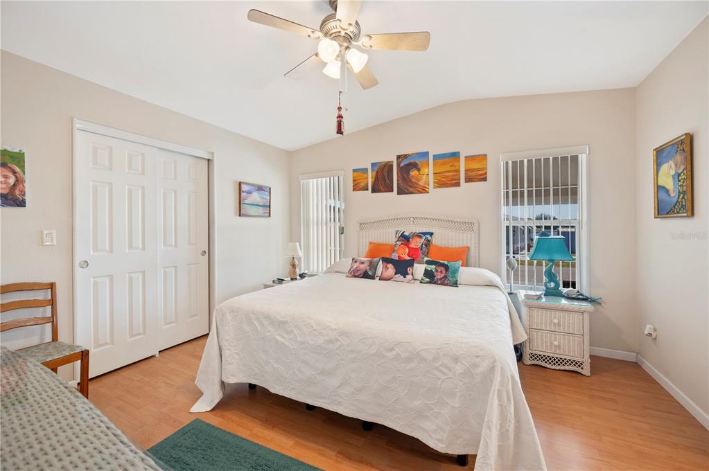 A bedroom features a king-sized bed, white closet doors, wood-look flooring, and a ceiling fan — 38 QUEEN OF WATERS STREET, LAKE WALES, FL