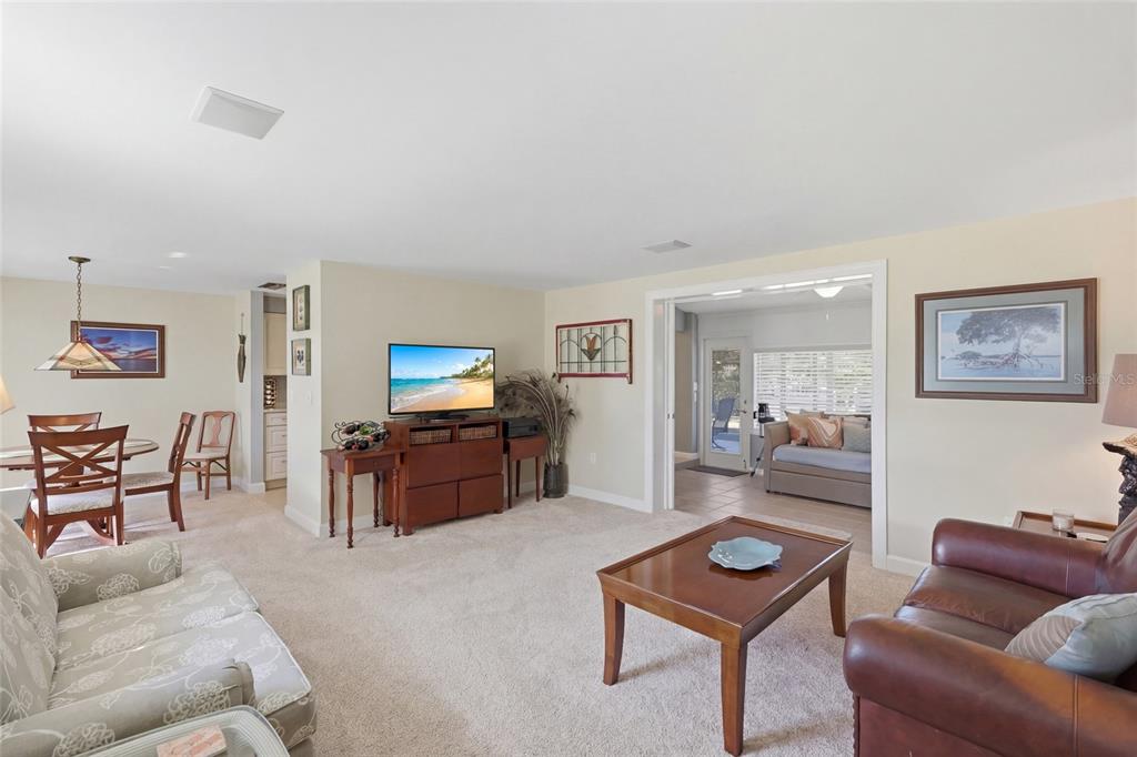 A living room with carpeted floors, a television, and an adjacent dining area — 109 TERN DRIVE, ANNA MARIA, FL