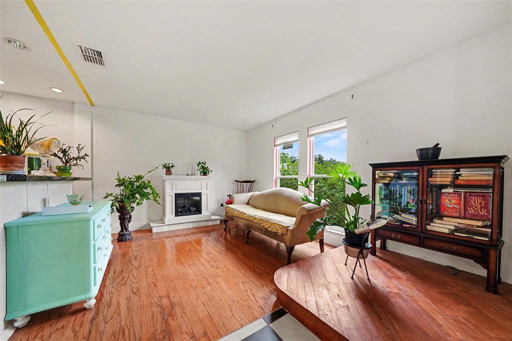 A living room features hardwood floors, a fireplace, a sofa, and a wooden display cabinet — 102 DORCHESTER SQUARE, LAKE MARY, FL