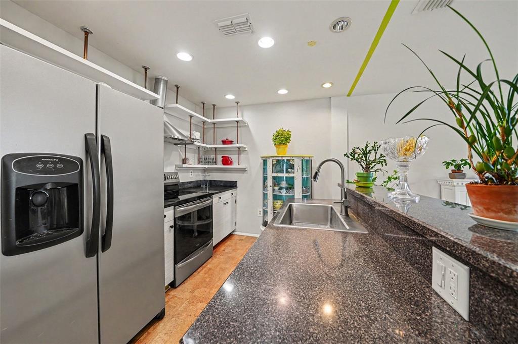 A kitchen features stainless steel appliances, dark granite countertops, and open shelving with pipe supports — 102 DORCHESTER SQUARE, LAKE MARY, FL