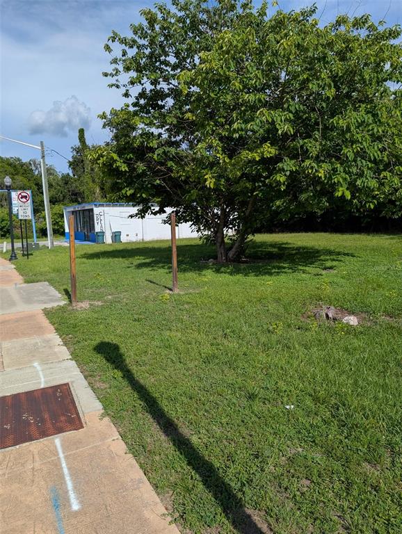 A grassy lot features a large tree, two wooden posts, and a white building behind — 822 SW BROADWAY ST, OCALA, FL