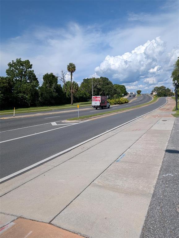 A paved road curves through a green landscape under a blue sky with clouds — 822 SW BROADWAY ST, OCALA, FL