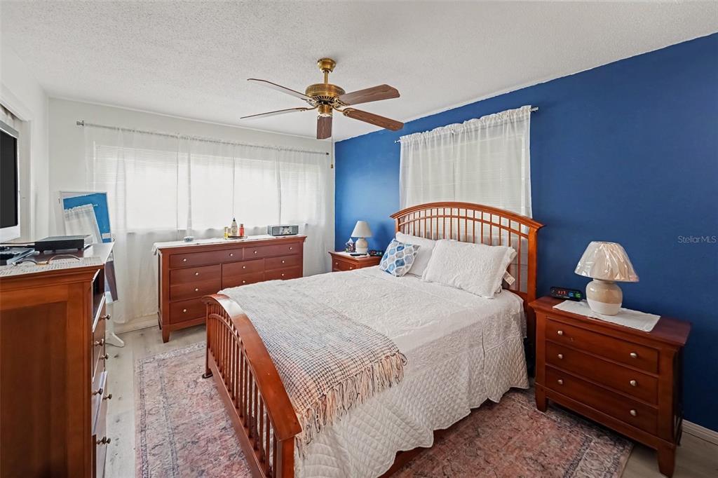 A bedroom features a wooden bed frame, a blue accent wall, and a wooden dresser — 6880 LAFAYETTE N UNIT 8, PINELLAS PARK, FL